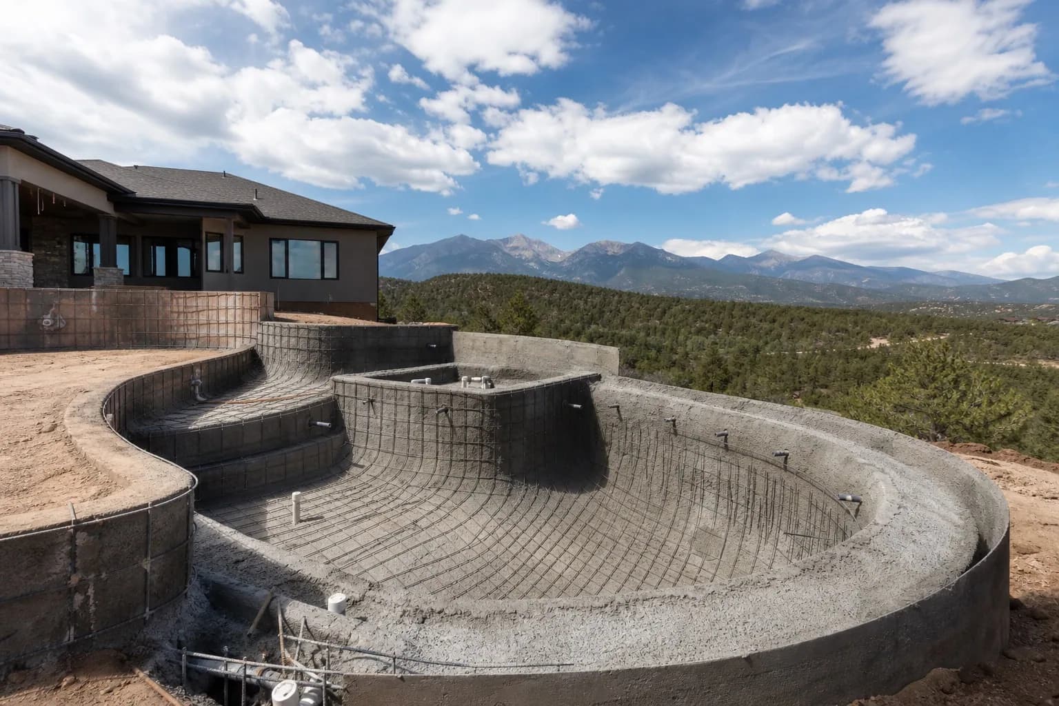 Custom residential pool under construction: excavation and structural phase in a Colorado backyard with mountain sky
