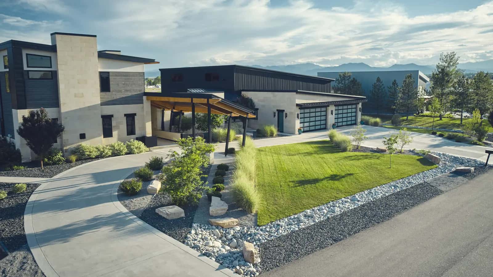 Modern Colorado home with covered outdoor living area, curved driveway, and designed landscape beds
