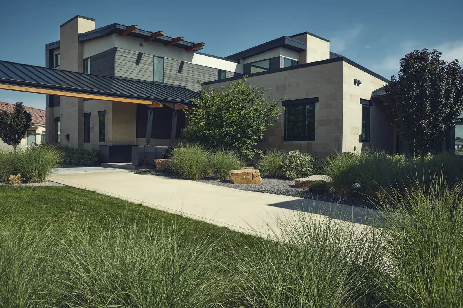 Modern home entry with lawn, decomposed granite walk, ornamental grasses, and boulder accents