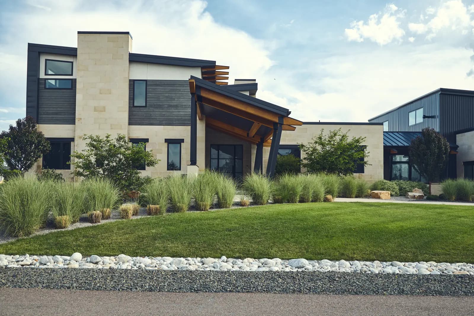 Modern stone and metal home facade with new lawn and rock-bordered grass beds