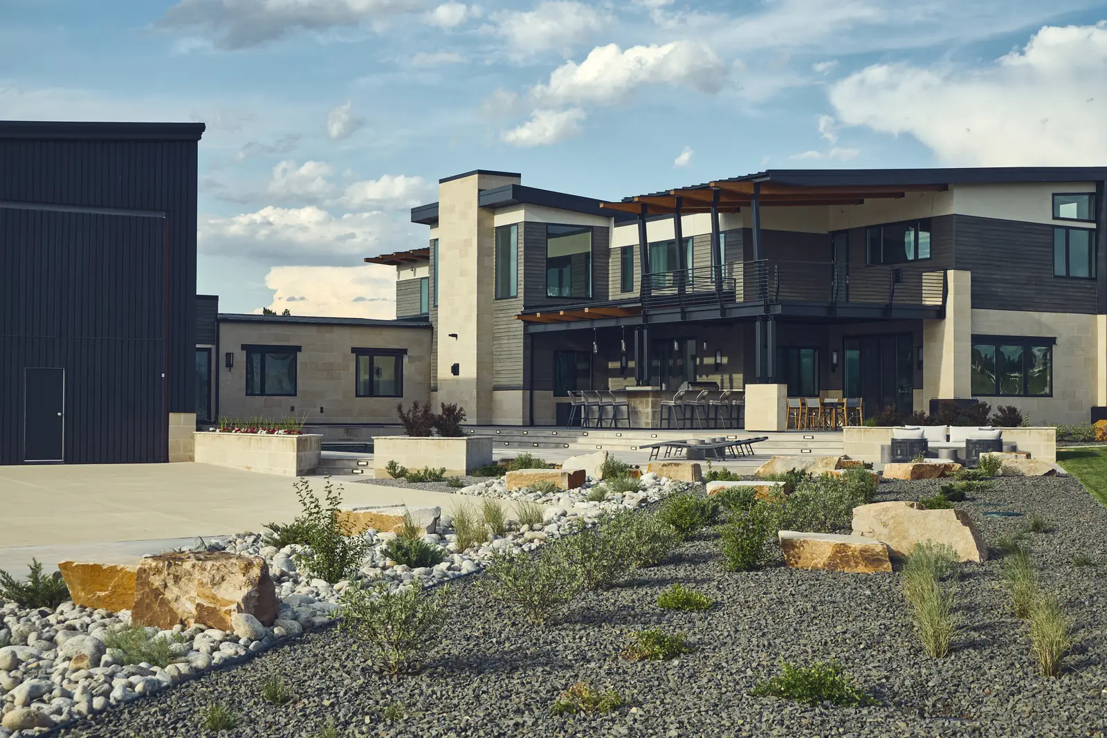 Terraced backyard with boulder retaining, gravel beds, and the modern home beyond
