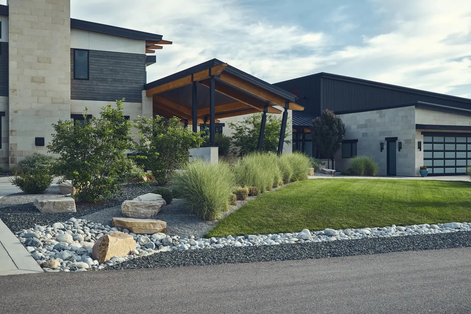 Covered patio corner with ornamental grasses, boulders, and river rock beds