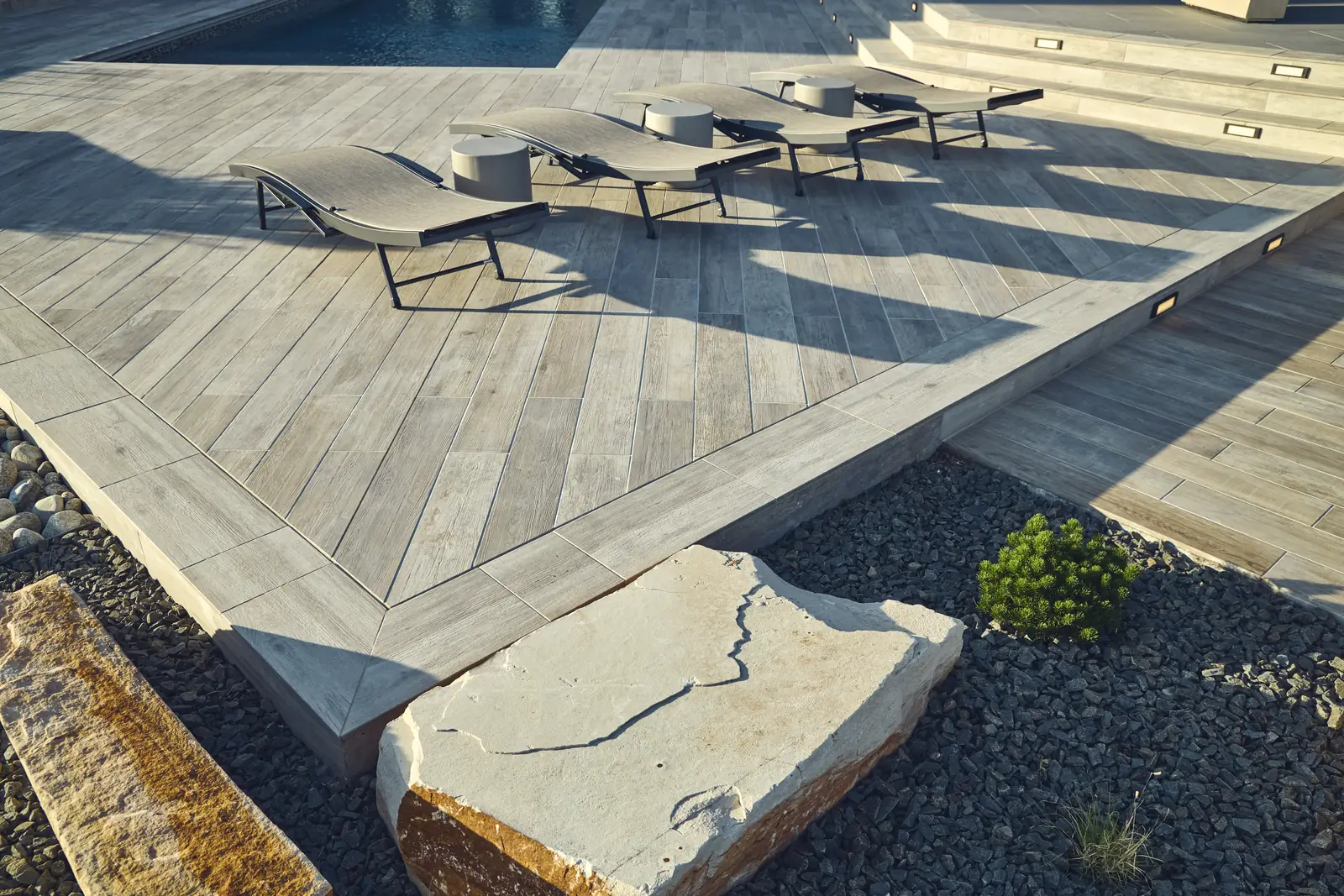 Deck corner with diagonal porcelain pavers, a large stone slab, and boulder accents