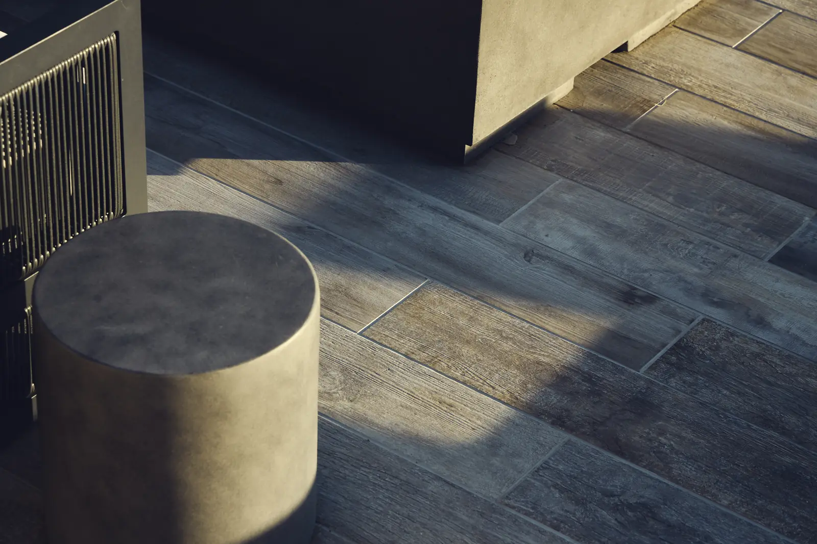 Round concrete stool on the porcelain paver patio beside a slatted screen